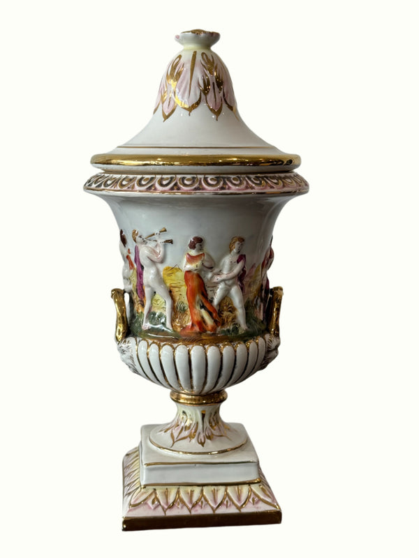 Decorative urn with intricate designs and figures on a plain background